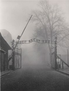 an old black and white photo of a gated entrance to a building on a foggy day