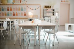 a room with several tables and chairs, one has a cup on top of the table