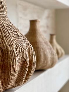 three vases sitting on top of a white shelf