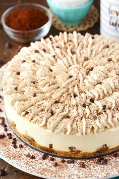 a cake sitting on top of a white plate next to bowls of chocolate chips and coffee