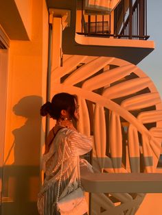 a woman leaning against a wall with her hand on the back of her shoulder,