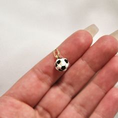 a tiny soccer ball charm is on someone's finger