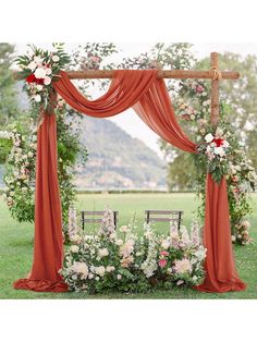 an outdoor wedding ceremony setup with red drapes and white flowers on the arbors