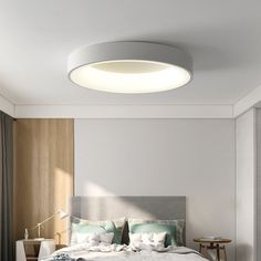 a bedroom with a bed, nightstands and a round light fixture on the ceiling