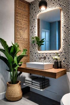 a bathroom with a sink and mirror next to a plant in a pot on the counter