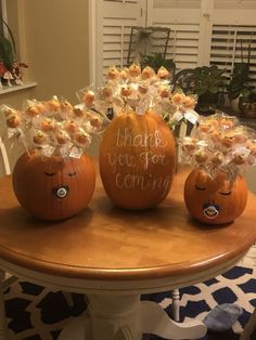 three pumpkins with flowers in them sitting on a table next to other pumpkins that say thank you for coming