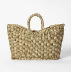 a large woven basket with handle on the front and bottom, sitting against a white background