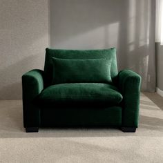 a green chair sitting on top of a carpeted floor in front of a window