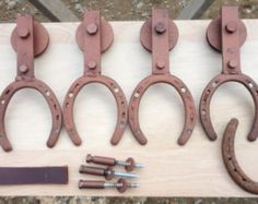 four pairs of horseshoes are sitting on a piece of plywood and screwdrivers