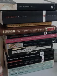 a stack of books sitting on top of a white table next to a cup and vase