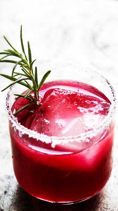 a red drink with a sprig of rosemary on top