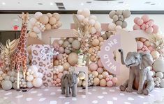 an elephant, giraffe and zebra are standing in front of a backdrop made out of balloons