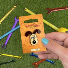 a person holding up a dog shaped pin in front of some colorful crayons