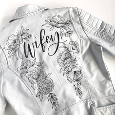 a white jacket with flowers on it and the word wife written in cursive writing