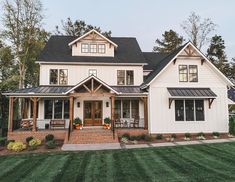 a large white house with black roof and two story windows on the front of it