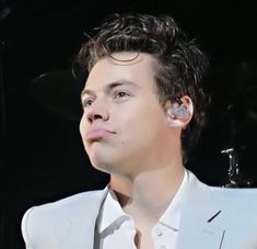 a close up of a person in a suit and tie with ear buds on his ears