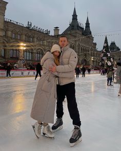 a man and woman are standing on an ice rink in front of a large building