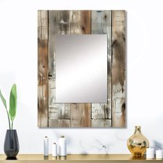 a mirror sitting on top of a wooden table next to a vase and candle holders