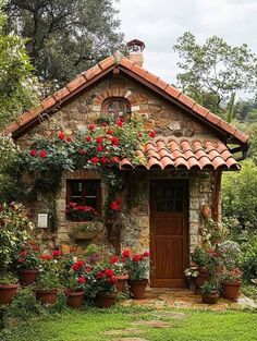 a small stone house with potted plants and flowers