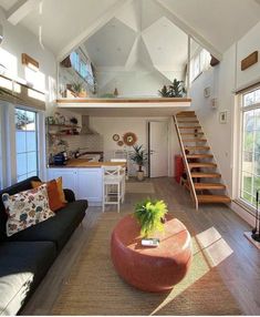 a living room filled with furniture and a stair case in the background, next to an open floor plan