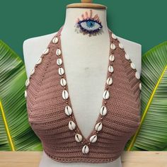 a mannequin wearing a pink top with shells and an eye brooch on it