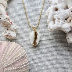 We love this fun and summery, beachy necklace. Answer the siren's song and get one for yourself or someone you love. Would make a great gift for the surfer or beach-lover in your life! A 14k gold electroplated cowrie shell dangles from a lustrous, high quality gold filled snake chain. The perfect summertime accessory! Chain length 16"✦ JEWELRY CARE ✦✧ Warm water and a soft cloth are the best thing you can do to maintain the beauty of your jewelry.✧ Jewelry polishing cloths work great and are non Gold Cowrie Shell As Gift, Gold Cowrie Shell Jewelry For Gift, Beach Jewelry With Charms In Ocean-inspired Style, Ocean-inspired Jewelry With Charms For Beach, Ocean-inspired Beach Jewelry With Charms, Handmade Gold Charm Necklace For Vacation, Ocean-inspired Gold Charm Necklaces For Summer, Gold Ocean-inspired Charm Necklaces For Summer, White Shell Charm Necklace Gift