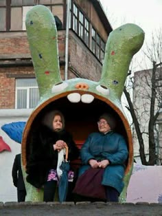 two women sitting in a fake rabbit shaped building