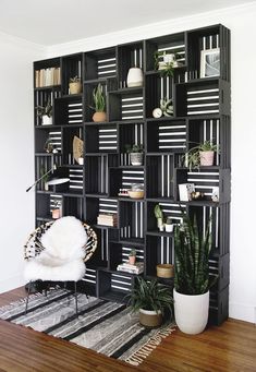 a living room filled with lots of bookshelves next to a white chair and potted plants