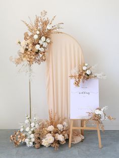 a white sign sitting on top of a wooden easer next to a flower arrangement