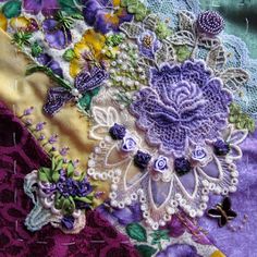 a close up view of an embroidered fabric with flowers and butterflies on it, as well as lace