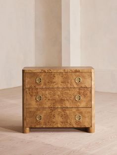 a wooden dresser sitting on top of a hard wood floor next to a white wall