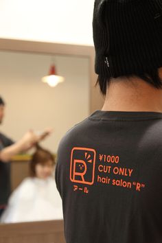 a man wearing a black shirt with an orange print on it and a woman in the background