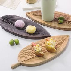 three wooden trays with food on them sitting on a table next to a cup