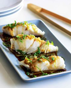 steamed halibut with fresh ginger on a blue plate next to chopsticks