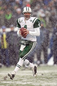 a football player running in the snow with a ball on his hand and people watching from the stands