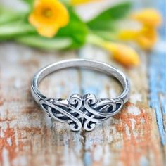 a silver ring sitting on top of a wooden table next to yellow tulips