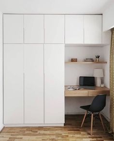 a room with a desk and some white cupboards