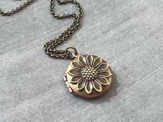 Small Vintage Sunflower Locket...  The locket I used to create this charming necklace is a vintage 1960's RAW BRASS and copper locket with a naturally aged patina.  I attached a sweet antiqued brass sunflower stamping to the center.  The chain is an antique brass plated soldered chain and it closes with a lobster claw clasp.  The locket and sunflower are made in the US!  The SHADE OF PATINA WILL VARY on each locket and sunflower stamping. This is a VINTAGE locket from the 1960's.  Some of the lo Vintage Yellow Gold Locket Necklace Gift, Elegant Floral Locket Jewelry, Gold Flower-shaped Locket Jewelry, Flower Garden Wedding, Antique Engraved Flower Pendant Locket Necklace, Sunflower Locket Necklace, Vintage Sunflower, Vintage Locket, Woodland Flowers