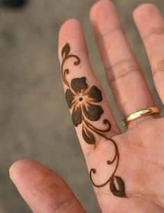 a woman's hand with a flower tattoo on it and a gold wedding band