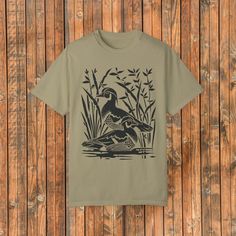 Comfort Colors Wood Ducks Block Print Tee - a blend of comfort and style featuring the beauty of nature. Crafted from soft cotton, this tee showcases a striking block print image of Wood Ducks, capturing the elegance of these graceful birds. Immerse yourself in the serene beauty of the design, capturing the essence of nature's tranquility. The Comfort Colors fabric ensures a soft and comfortable feel against your skin, making this tee perfect for everyday wear, outdoor adventures, or simply loun Khaki Graphic Print Short Sleeve Tops, Khaki Short Sleeve T-shirt For Outdoor, Khaki Relaxed Fit Graphic Tee, Khaki Graphic Tee With Relaxed Fit, Outdoor Screen Print T-shirt, Outdoor T-shirt With Screen Print, Outdoor T-shirt With Screen Print And Short Sleeves, Outdoor Short Sleeve T-shirt With Screen Print, Short Sleeve Graphic Tee With Printing