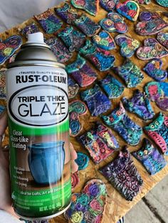 a person holding a can of spray paint next to some cookies on a wooden table