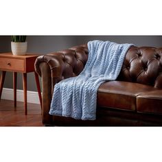 a brown leather couch with a blue blanket on it