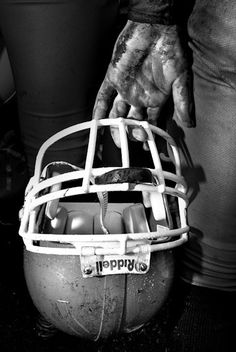 a football helmet that has been covered with mud and is being held by someone's hands