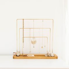 a white shelf with gold jewelry on it and a wooden tray holding various necklaces