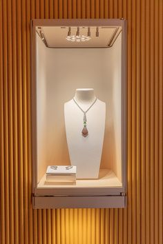 a white display case with a necklace and other items in it on top of a table