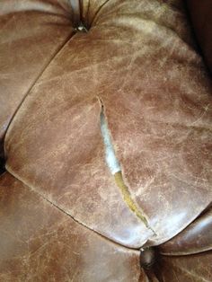 a close up of a brown leather couch with a hole in it