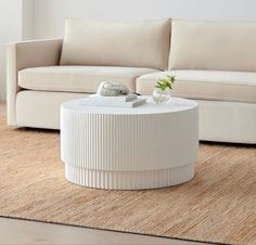 a white coffee table sitting on top of a rug in front of a beige couch