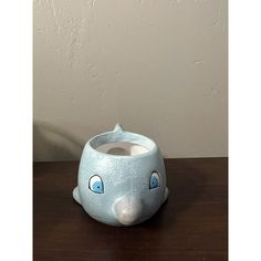 a blue elephant shaped vase sitting on top of a wooden table next to a wall