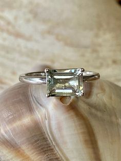 This classic East West solitaire setting contains a beautiful 2.00ct genuine prasiolite. The emerald cut stone measures approximately 8x6mm. The ring is available in sterling silver, and 14k white, yellow, or rose gold. This ring makes a great promise or engagement ring. Please send me a message if you need a size not listed. * This ring can be customized with any color center stone. All items are handmade by me in my shop in Woodbridge, NJ. Please message me with any questions. Shipping within Classic Emerald Cut Ring With Ethically Sourced Gemstones, Classic White Sapphire Gemstone Ring, Classic Sapphire Ring With Radiant Cut Center Stone, Classic Sapphire Ring With Radiant Cut, Classic Green Amethyst Ring As Gift, Classic Green Amethyst Ring For Gift, Classic Green Amethyst Ring Gift, Emerald Cut Sapphire Solitaire Promise Ring, Classic Emerald Cut Topaz Ring With Prong Setting