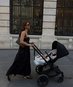 a woman walking down the street with a baby in a stroller